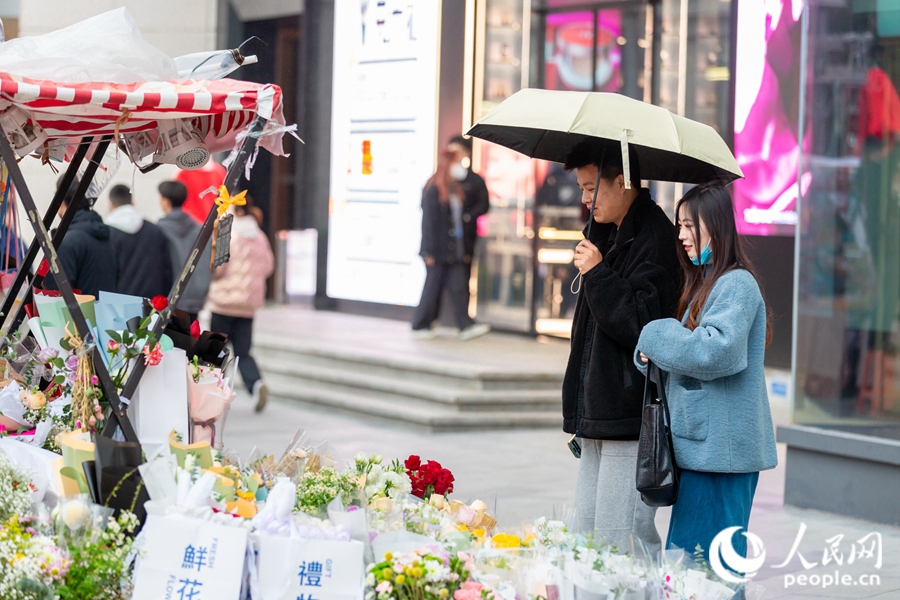 年輕情侶在鮮花小攤前駐足?？道跀z
