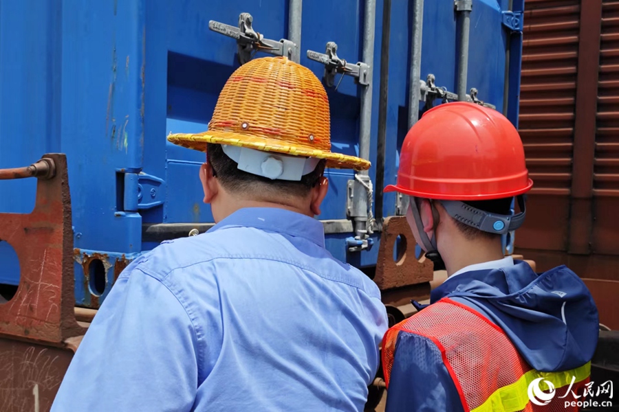 集裝箱裝上平車后，工作人員檢查箱門閉合情況。人民網 黃東儀攝