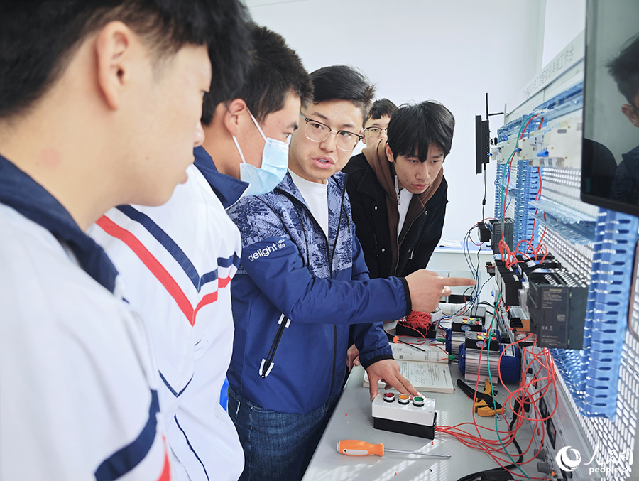 圖為寧夏飛毛腿技工學(xué)校在校生在老師的指導(dǎo)下學(xué)習(xí)基本電路的安裝調(diào)試方法。人民網(wǎng) 黃東儀攝