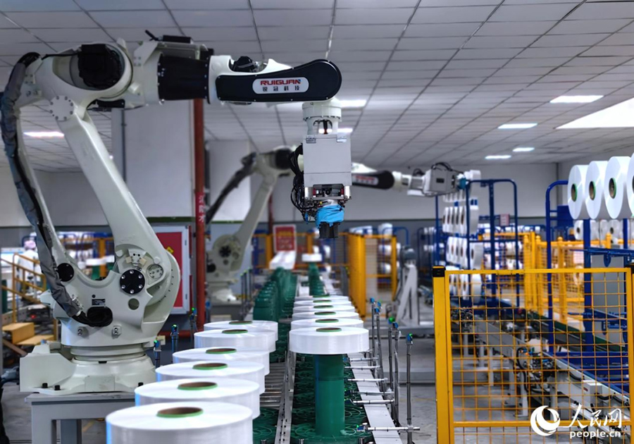 恒申集團(tuán)化纖車間里的機(jī)械臂已取代人工進(jìn)行批量搬運。人民網(wǎng) 葉青卿攝