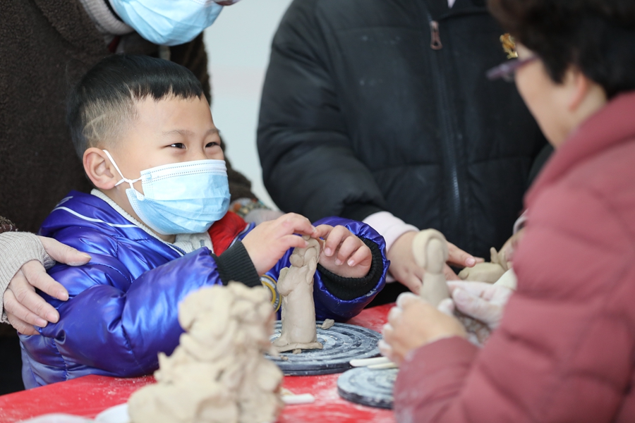 在泉州南站的“非遺集市”上，小旅客好奇地體驗(yàn)佛像雕塑工藝。鄒陽(yáng)攝
