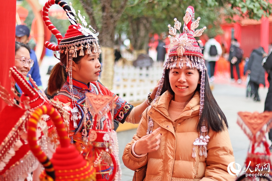 游客（右）體驗(yàn)畬族頭飾。人民網(wǎng) 李昌乾攝