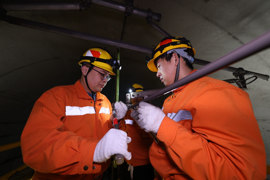 00后接觸網(wǎng)工張烘萊（右一）和工友在檢查接觸網(wǎng)定位裝置。胡鵬攝