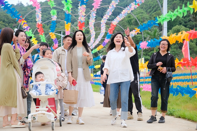 石竹街道洋梓村駐村第一書記吳炎芳（一排右二）帶游客體驗(yàn)花千谷主營(yíng)地（一期）娛樂項(xiàng)目