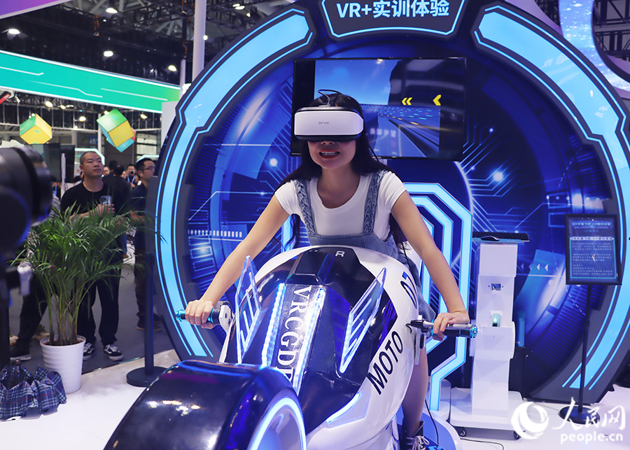觀眾頭戴VR眼鏡，體驗坐在摩托車上風馳電掣的快感。人民網(wǎng) 黃東儀攝