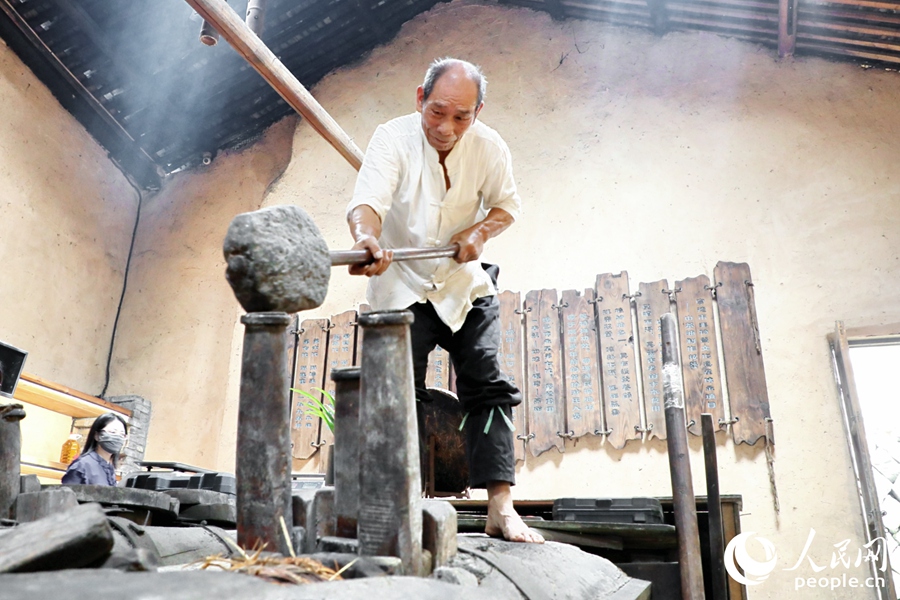 從事古法山茶油制作50年的游信玉現(xiàn)場掄錘榨油。人民網(wǎng) 李唯一攝
