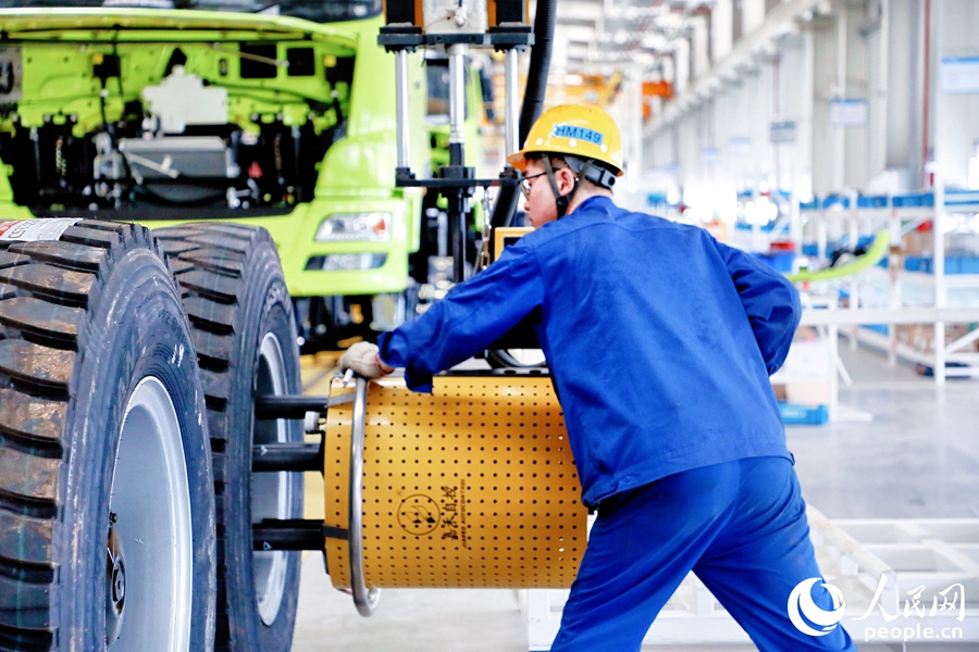 工人使用車輪螺栓擰緊機(jī)加固新能源礦卡的輪胎。人民網(wǎng) 李唯一攝