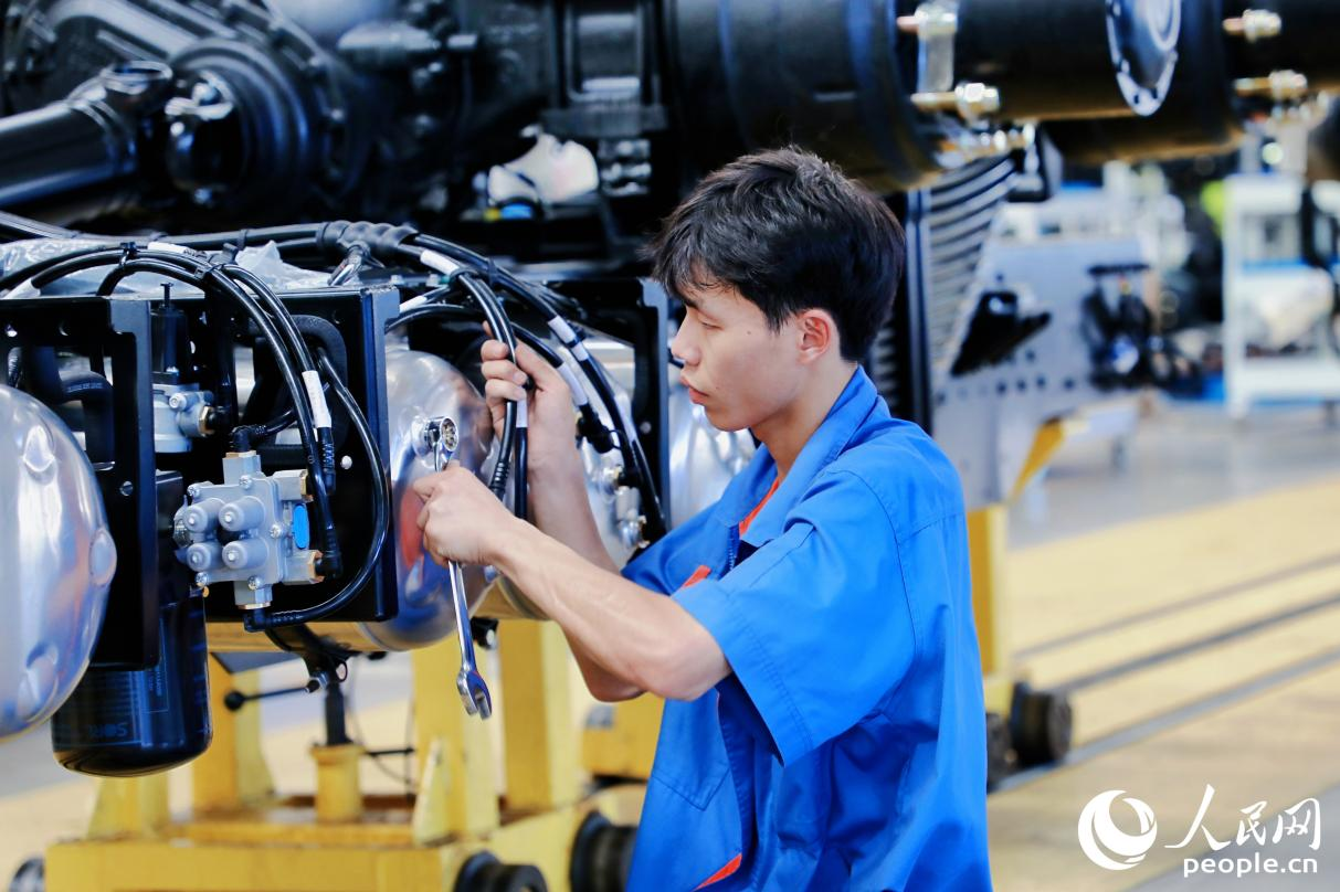工人將整車底盤的螺絲釘擰緊。人民網(wǎng) 李唯一攝