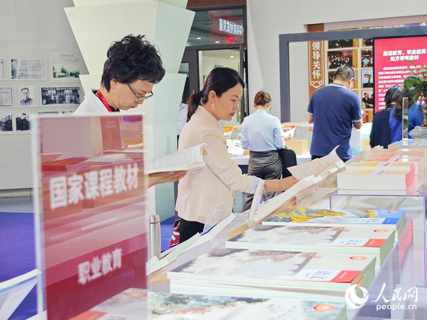 與會人員參觀成果展。據(jù)統(tǒng)計，目前中小學三科統(tǒng)編教材、高校思政課教材已全面融入習近平總書記地方重大實踐與重要論述有關(guān)內(nèi)容。人民網(wǎng) 黃東儀攝