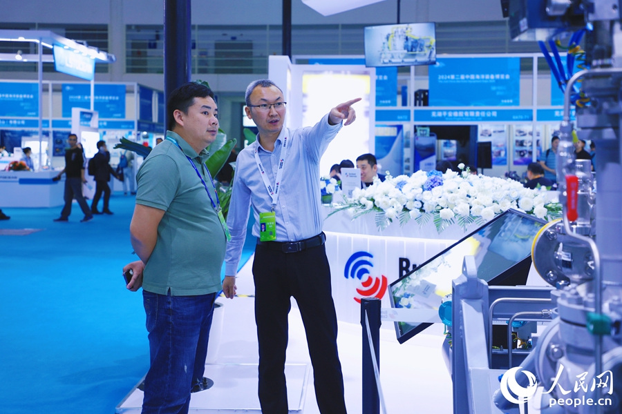 參展商向觀眾介紹迷宮式船用壓縮機有關(guān)情況。人民網(wǎng) 李唯一攝