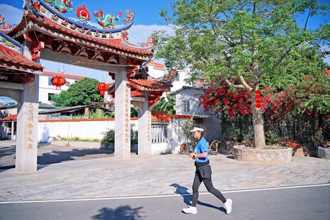 在特色建筑映襯下，一名選手在村道上奔跑。漳州市龍文區(qū)融媒體中心供圖