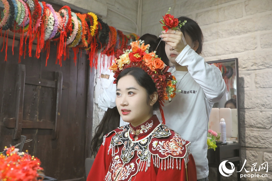 在秀發(fā)被盤(pán)成圓髻后，由鮮花串成的花圍被簪在頭上。人民網(wǎng) 李唯一攝