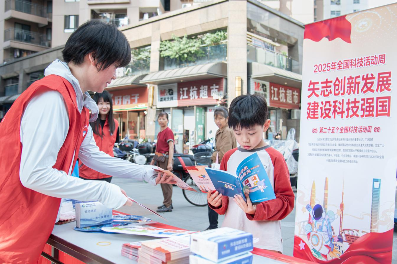 2025年全國科技活動周現(xiàn)場，志愿者向小學生遞發(fā)水利科普資料。陳美蓉攝