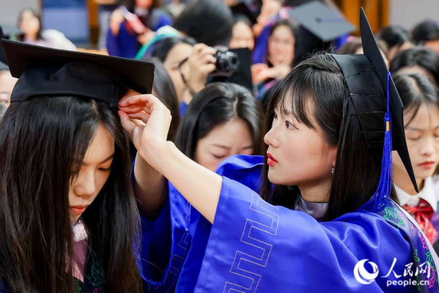 畢業(yè)生互相整理儀容。人民網(wǎng)記者 陳博攝