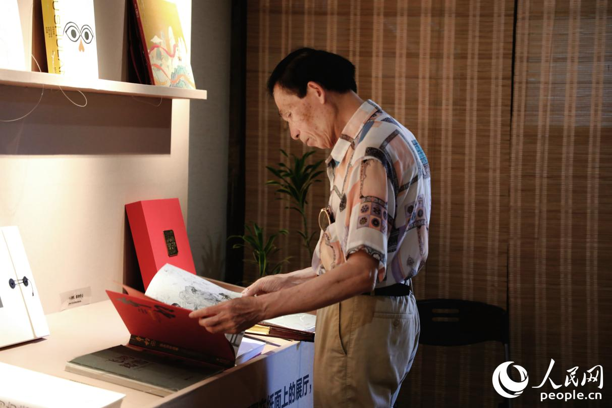 一位老人翻閱展出書籍。人民網(wǎng) 李唯一攝