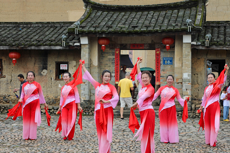 在土樓前，南靖土樓紅妹子宣講隊(duì)表演的《南靖土樓展新貌》，以通俗的唱詞講透惠民政策，優(yōu)美的舞姿展現(xiàn)鄉(xiāng)村新顏。南靖縣融媒體中心供圖