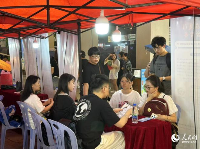夜市招聘會(huì)上，求職大學(xué)生正在與用人單位進(jìn)行交流。人民網(wǎng)記者 張萌攝