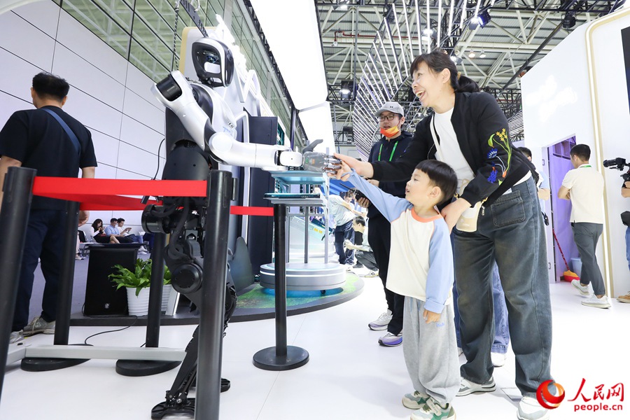 第八屆數(shù)字中國(guó)建設(shè)峰會(huì)上，小朋友和機(jī)器人互動(dòng)握手。人民網(wǎng) 陳永整攝
