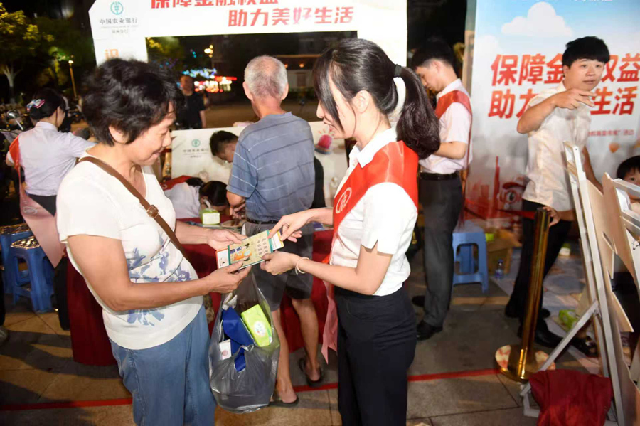 農(nóng)行漳州分行工作人員向市民發(fā)放宣傳折頁和漫畫手冊。蔡淇斌攝