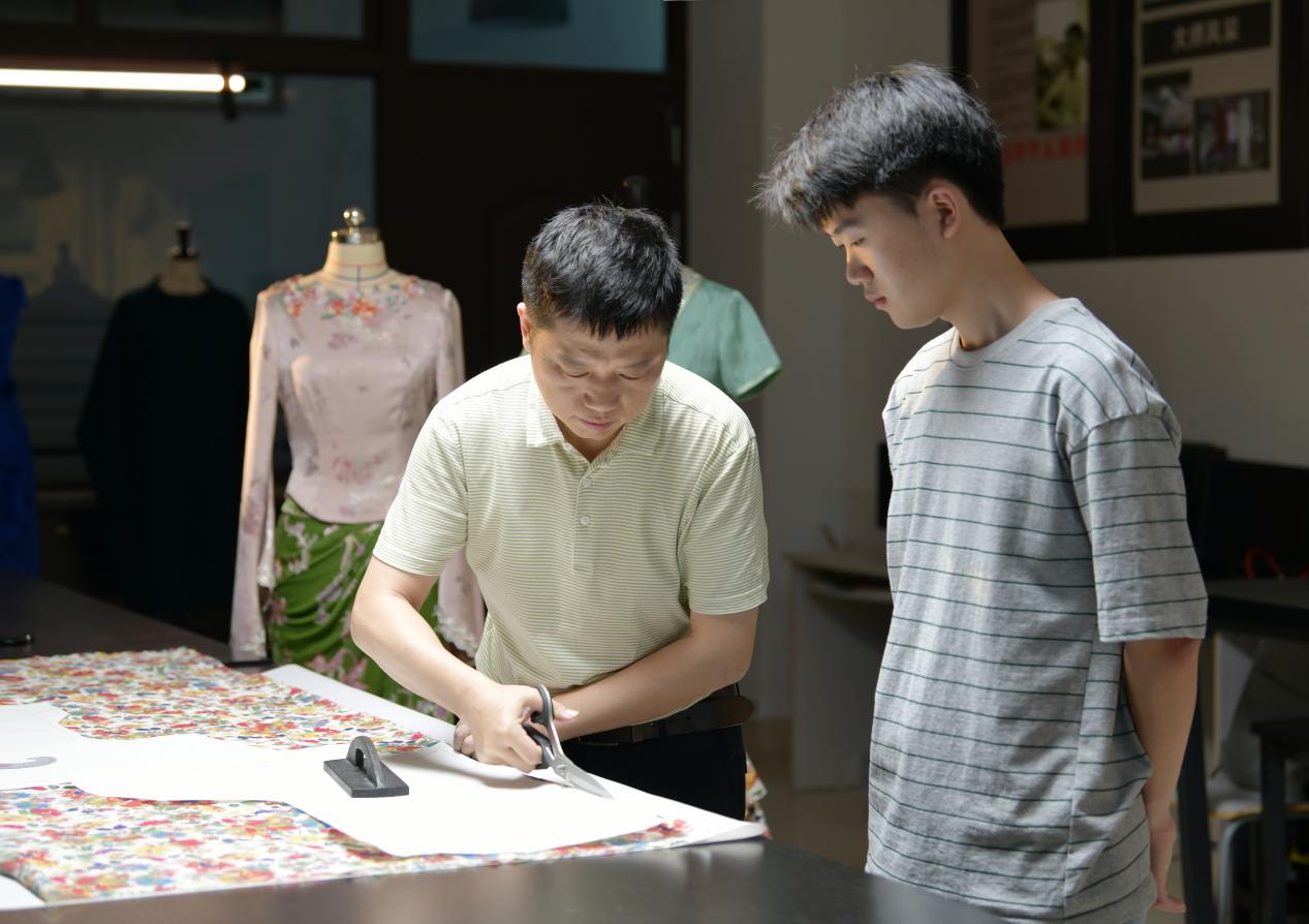 封衛(wèi)平與學(xué)生設(shè)計服裝版型。