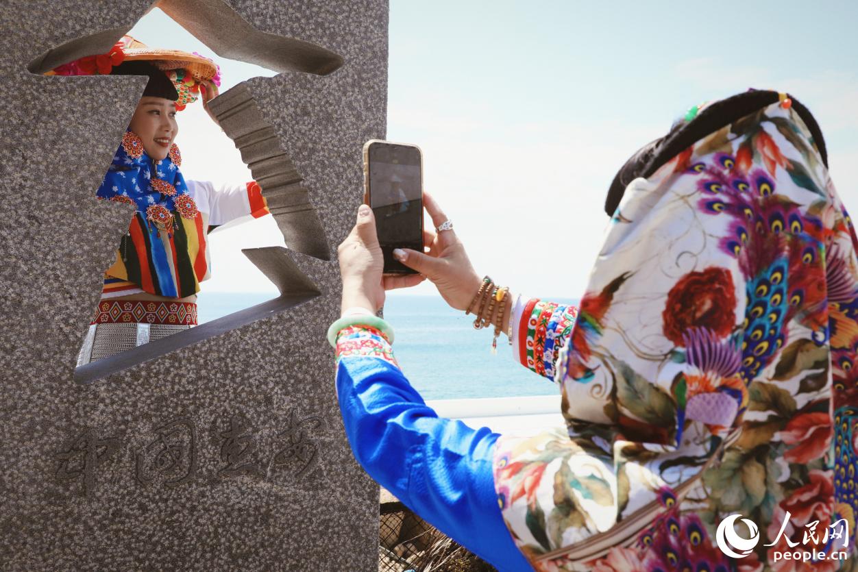 游客身著惠女服飾在海邊“打卡”。人民網(wǎng) 李唯一攝