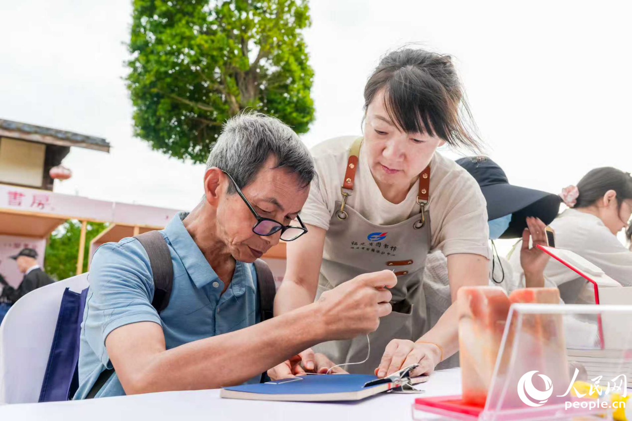 市民在“八閩書房”書香市集體驗線裝書裝幀。人民網攝