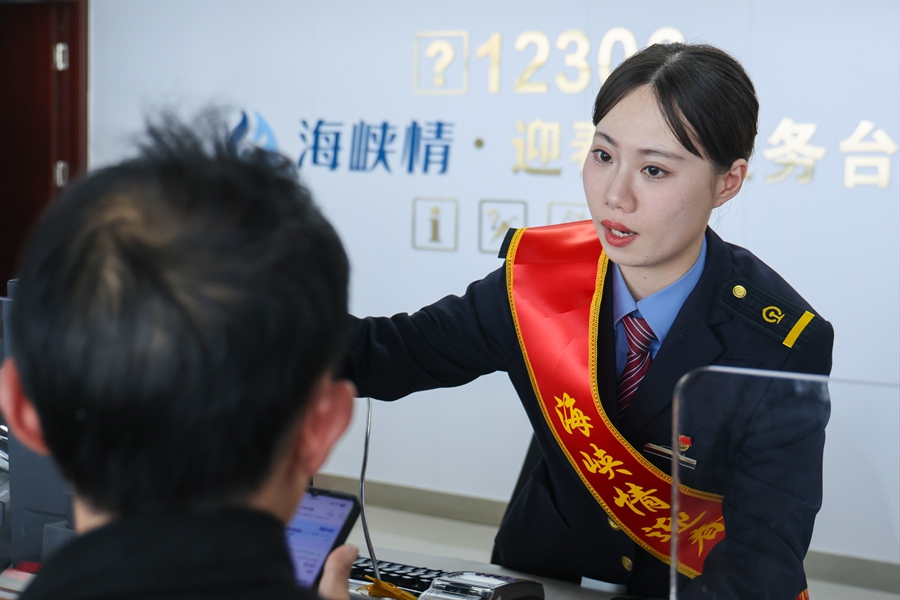 三明北站海峽情·迎春花服務臺工作人員正在引導旅客進站候車。張海根攝