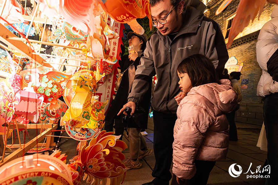 家長(zhǎng)帶著孩子選購(gòu)手提花燈。實(shí)習(xí)生 李雨澤攝