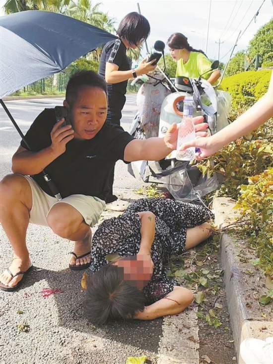 鄧彥撥打報(bào)警電話并撐起雨傘為受傷女子遮陽(yáng)。另外兩位熱心女士也一起幫忙。視頻截圖